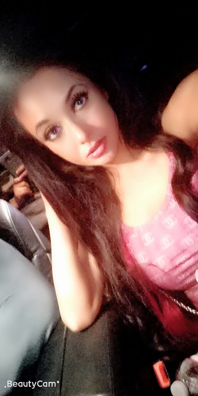 Jennifer Jorgensen Ahmed in a pink logo top taking a car selfie at night
